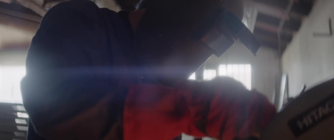 A man works in a workshop with a protective mask on