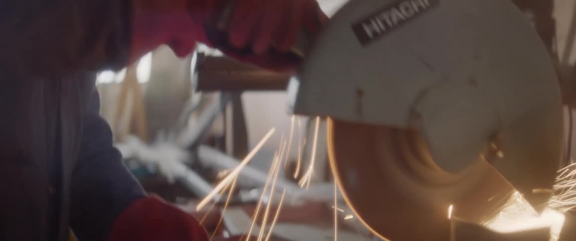 A man is using a circular saw on metal which causes sparks to fly