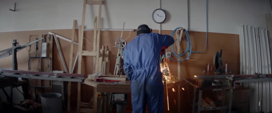 A man is using a circular saw as he works at a workbench inside during the day
