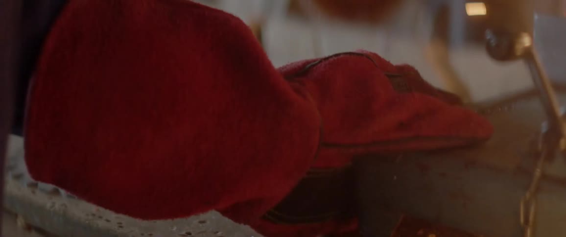 A gloved hand holds something near a machine that is throwing sparks