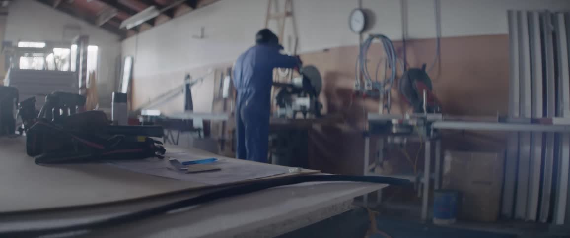 A man uses a chop saw in a workshop