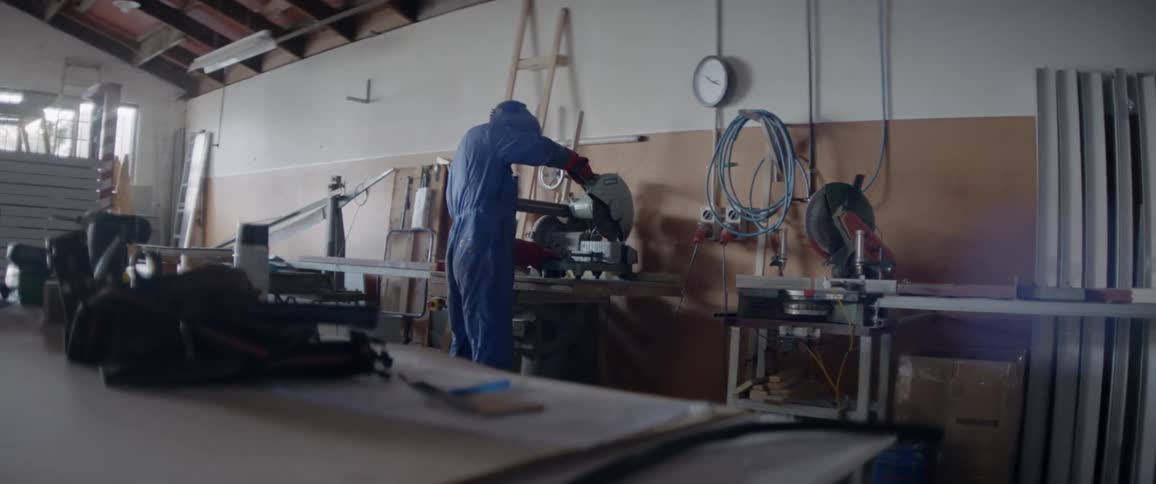 A man uses a chop saw in a workshop