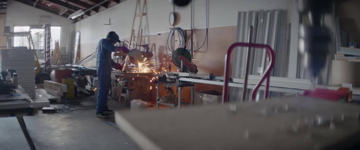 A man uses a chop saw in a workshop