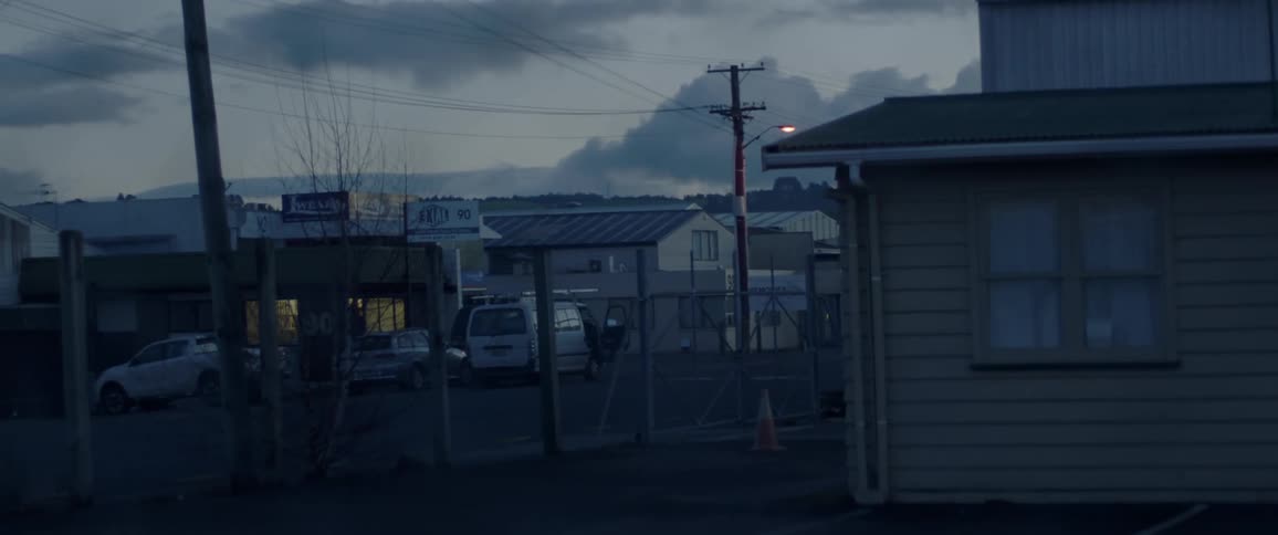 A car travels down a town road at dusk