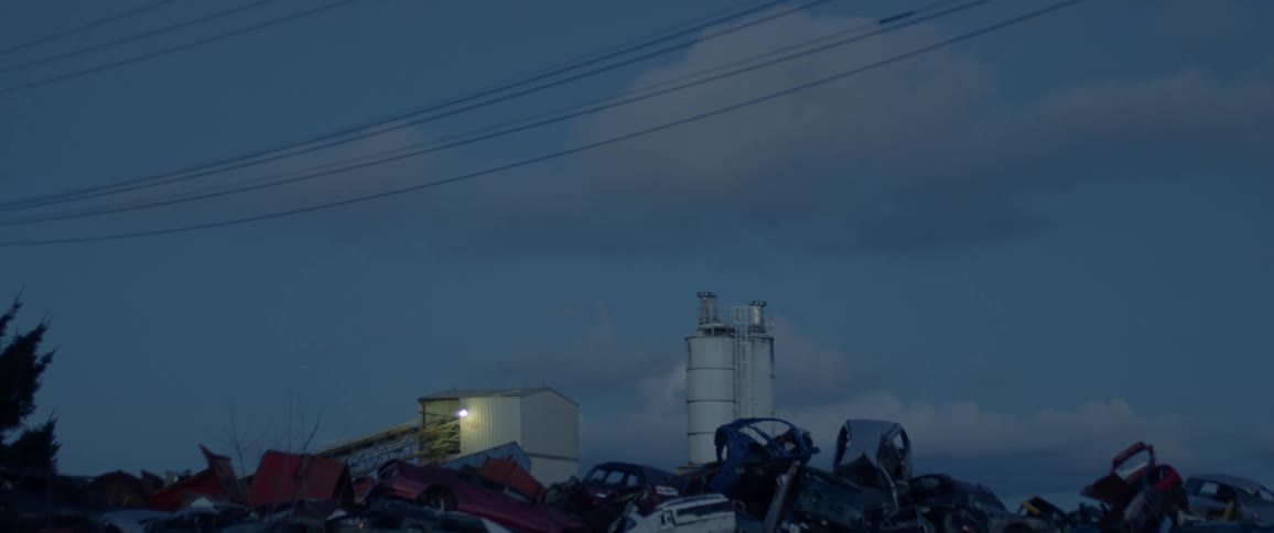 Old cars are stacked up in a junkyard