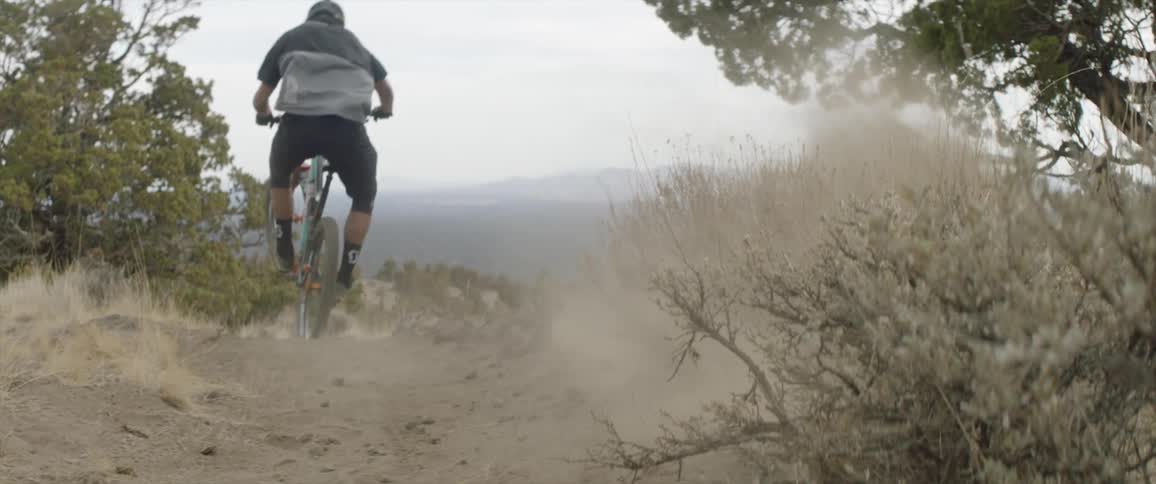 A man is riding a mountain bike on a dirt trail during the day