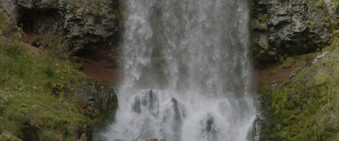 Water falls off the side of a stone cliff