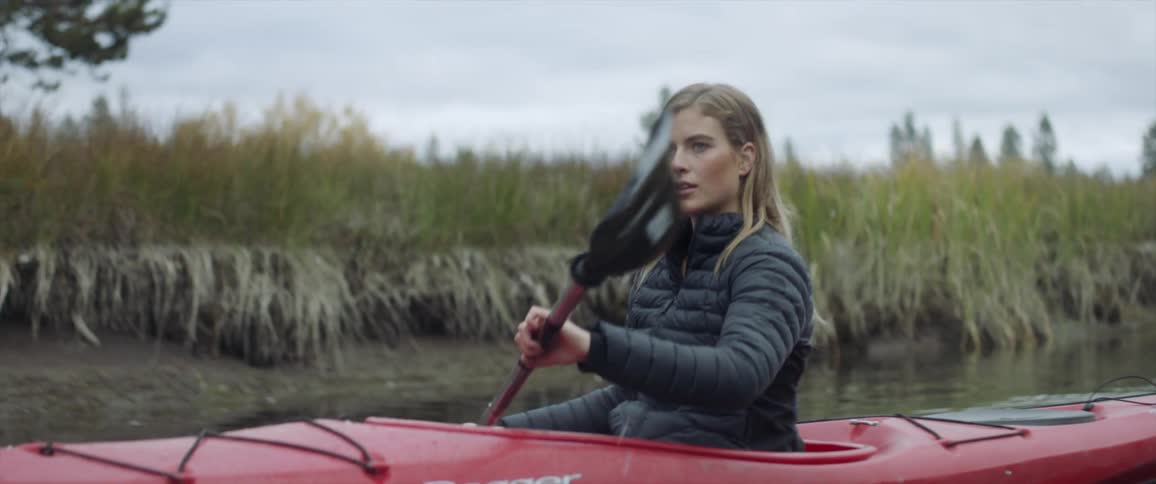 A woman paddles a kayak down the river