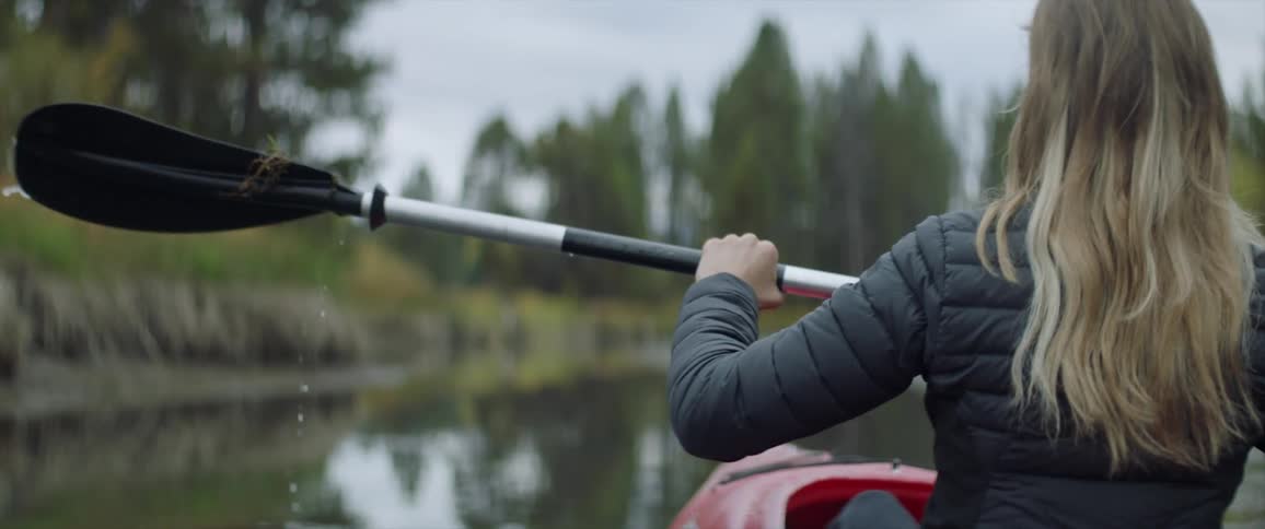 Woman paddles a kayak in a pond