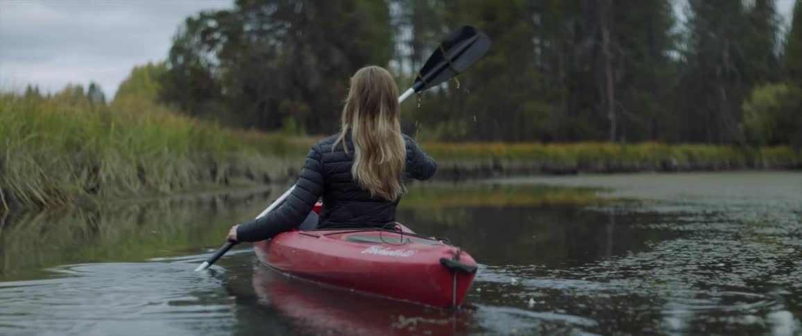 A woman kayaks in a pond