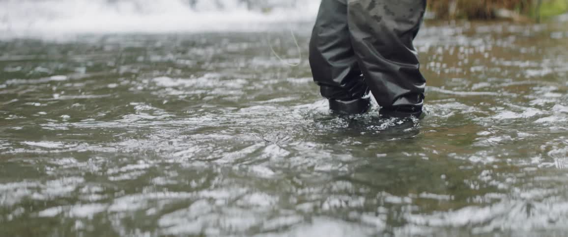 Man in hip waders fishes in a creek