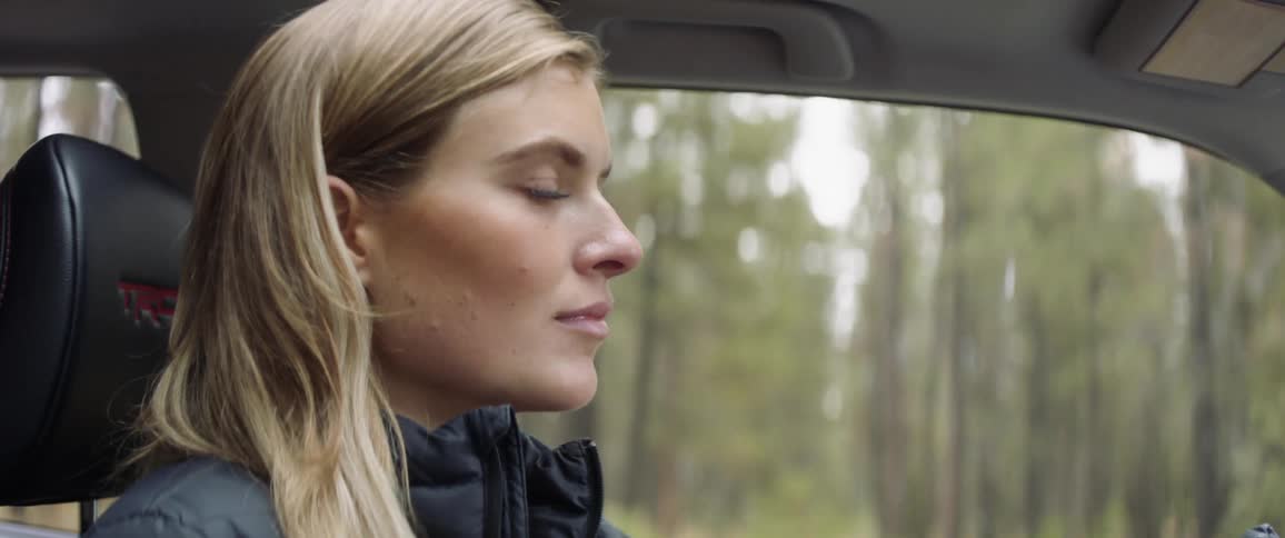 A woman is driving in a car through the woods