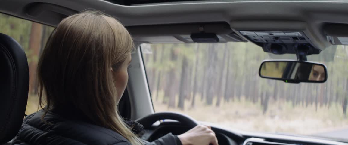 A woman drives in a forest
