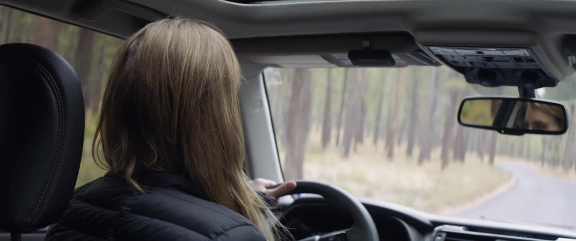 A woman drives in a forest