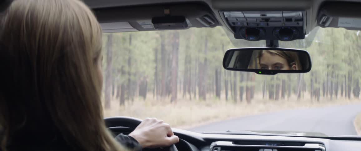 A woman drives on a forest road