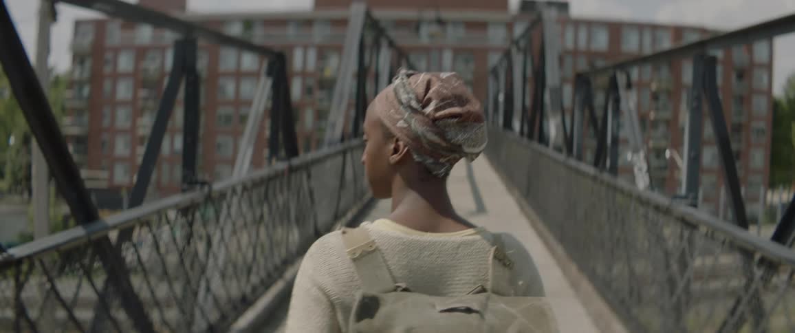 A girl wearing a backpack and headscarf walks across a pedestrian walkway
