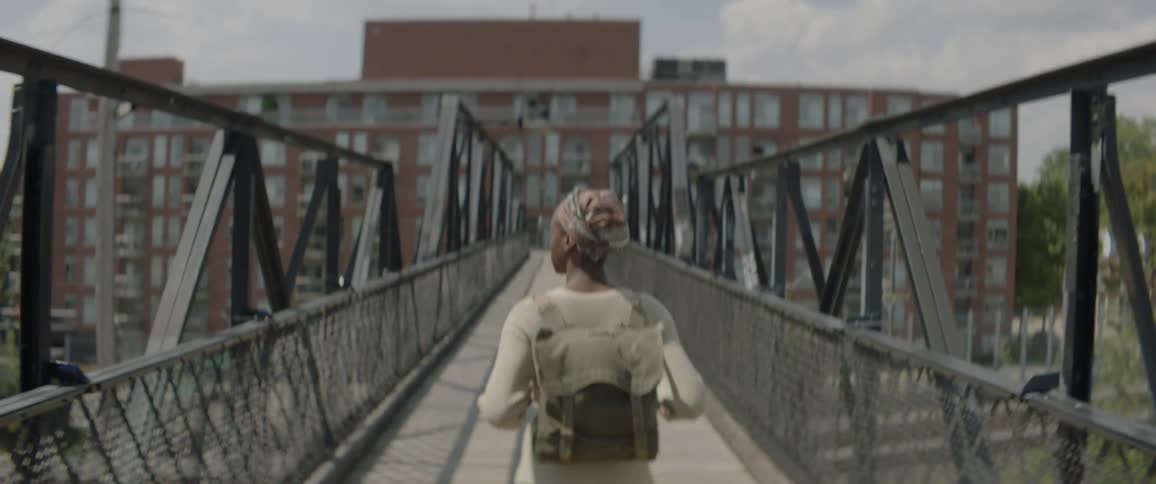 A girl wearing a backpack crosses over a road using a pedestrian walkway