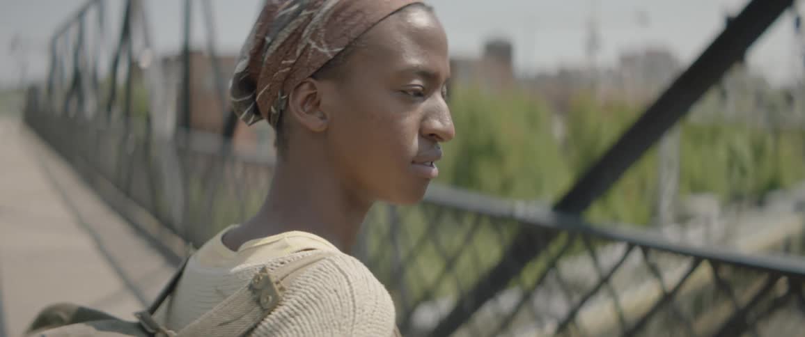 A person wearing a backpack crosses a bridge