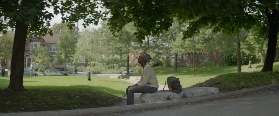 Woman sits on a rock in a park