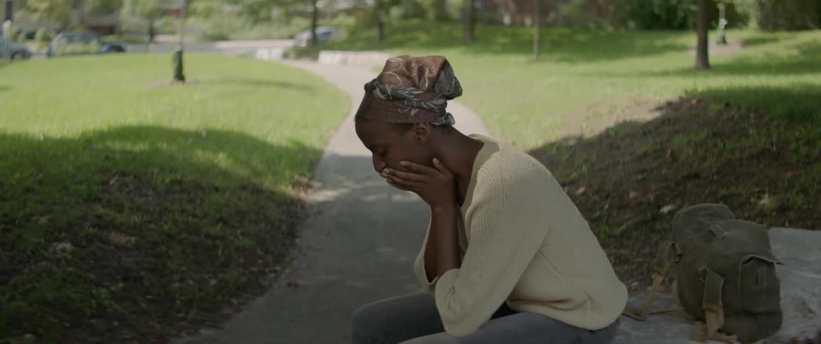 A woman sits in a park with her head resting on her hands