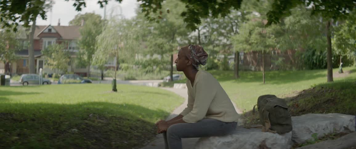 Woman sits on a rock in a park