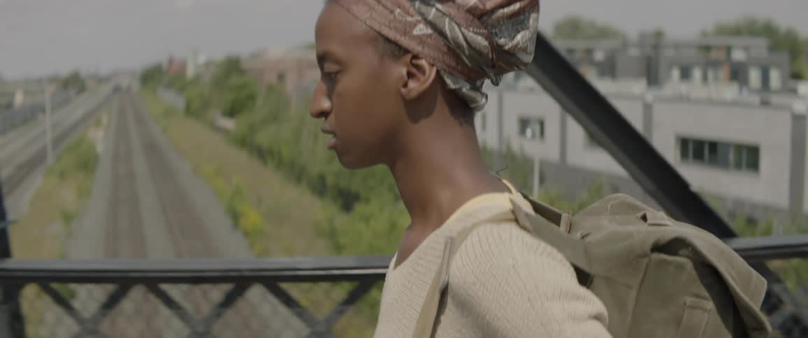 A woman carrying a backpack walks over a bridge