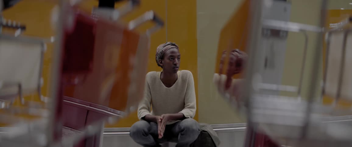 A person sits against a yellow striped wall