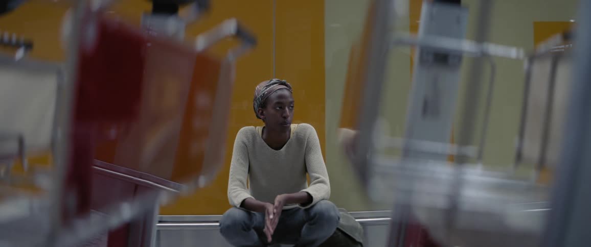 A woman is squatting down against a wall in an airport