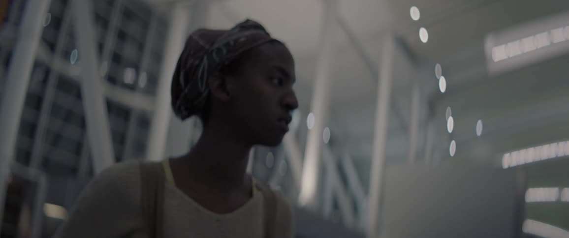 A woman is standing in the middle of a large building looking confused