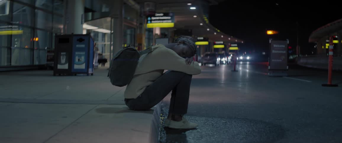 Woman sits on a curb outside an airport