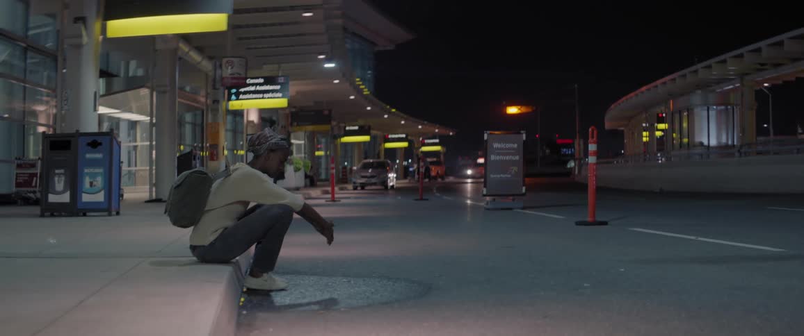 Woman sits on the edge of a sidewalk at a station