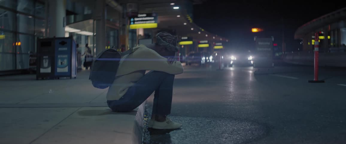 A person sits on the curb outside an airport