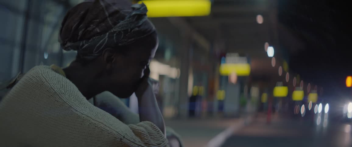 Woman sits on a curb at an airport