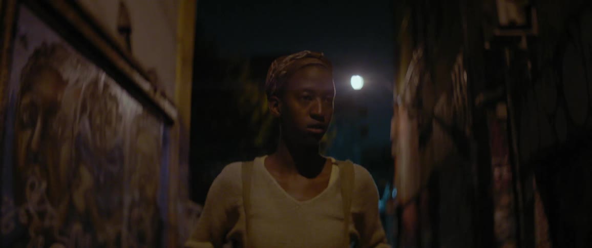 Woman walks alone in a city alley at night