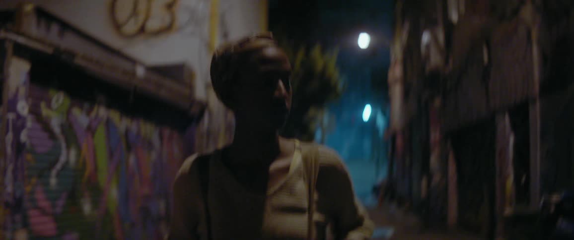 Woman walks alone in a city alley at night
