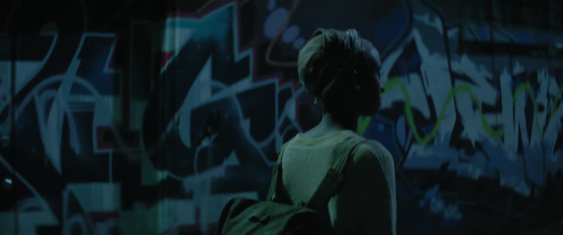 A woman walks by a graffiti covered wall