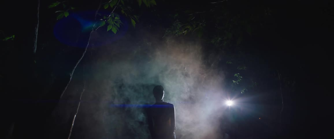 A person is swaying and leaning over as they stand outside at night