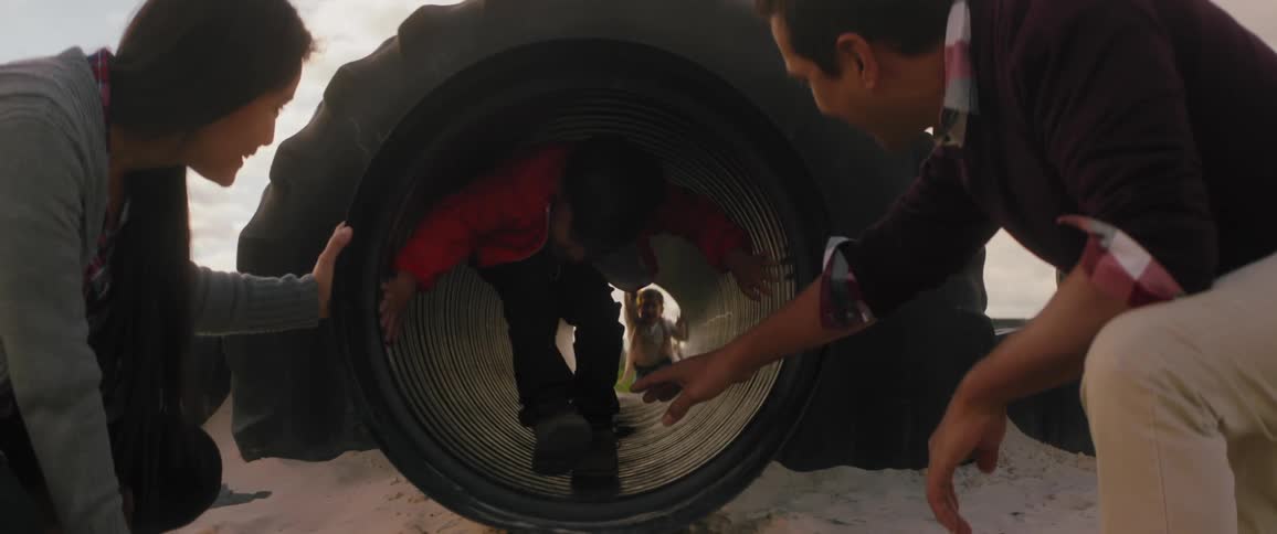 A young child crawls through a pipe on a playground