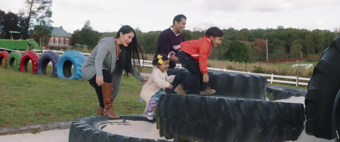 A family plays on large tires on a farm