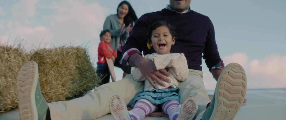 A man goes down a slide with a young girl