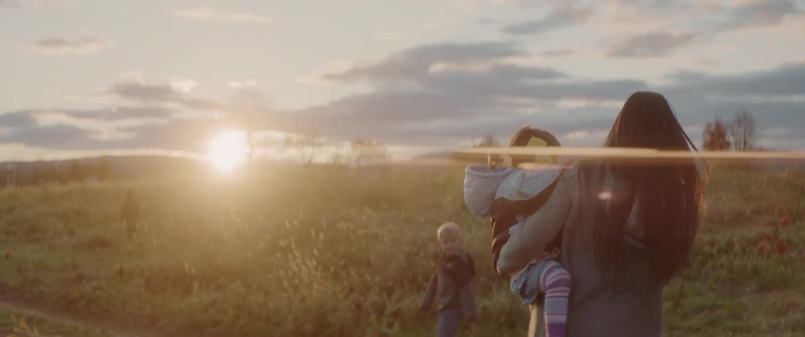 A family walks in a rural field at sunset