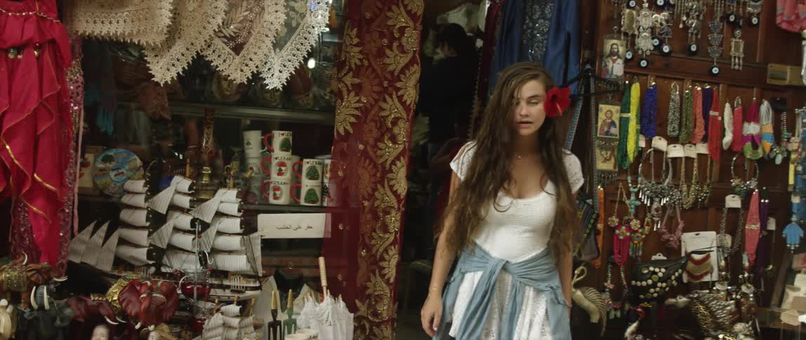A woman exits a shop on a sunny day