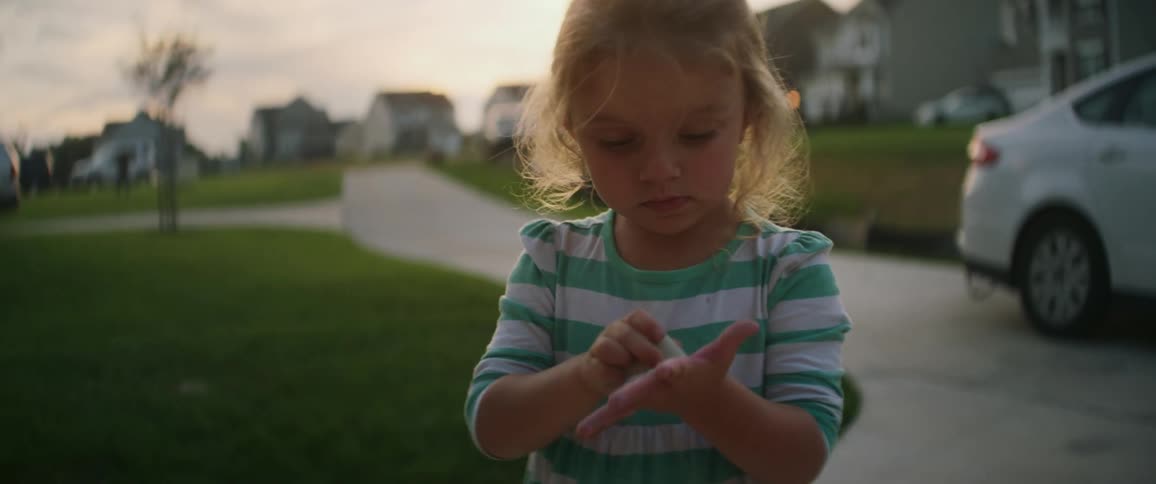 Child colors on her hand with sidewalk chalk