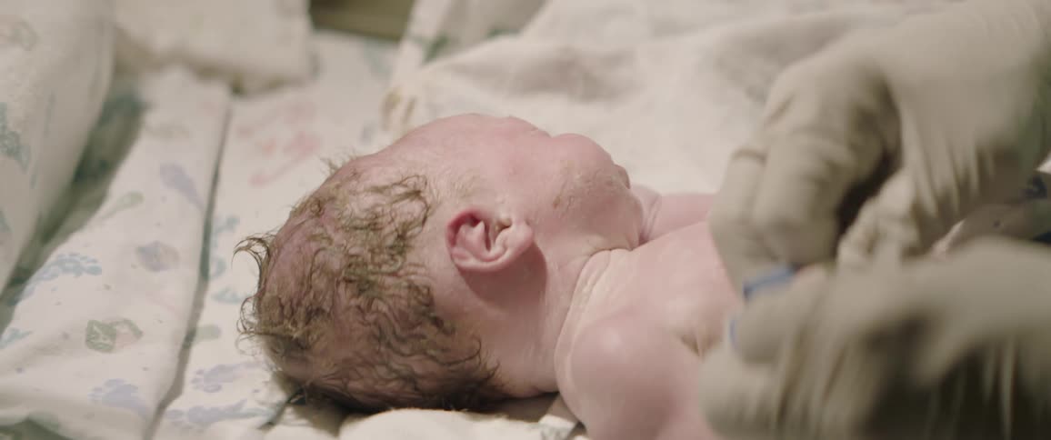 Person wearing gloves wipes off a crying infant