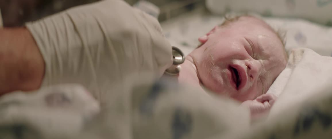 A stethoscope is used on a crying newborn