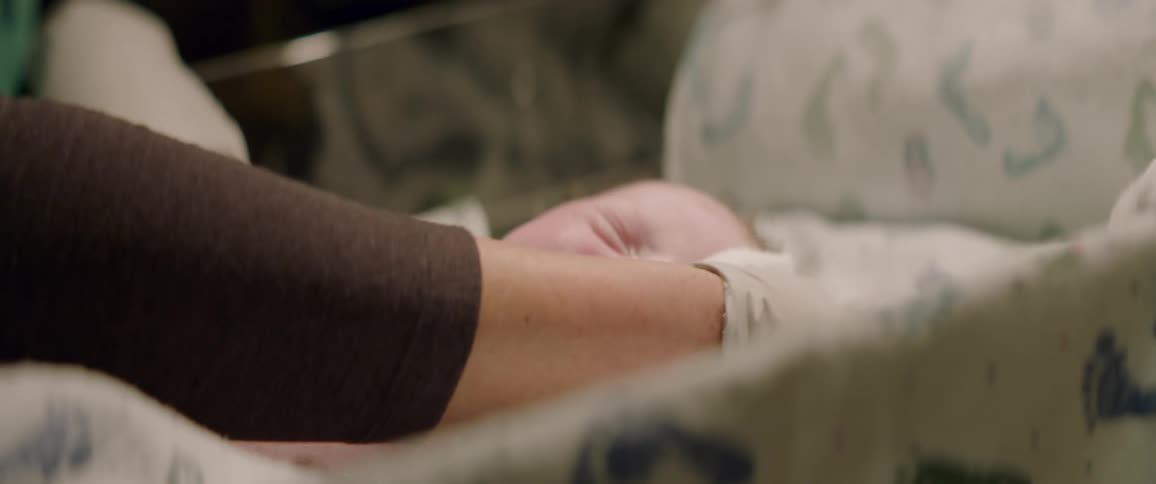 Person wearing gloves wipes off a crying infant