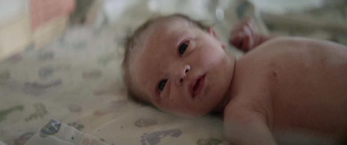 Baby moves its arm as it lays in a crib