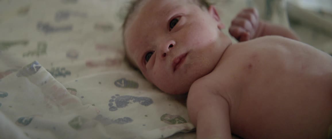 Baby lays in a crib as it looks around