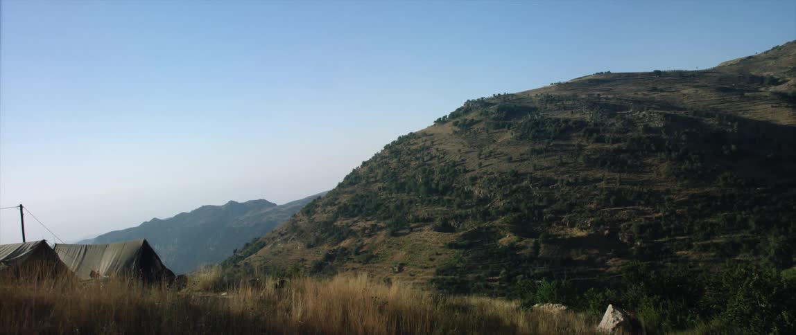 A tent is sent up on a mountain range on a sunny day
