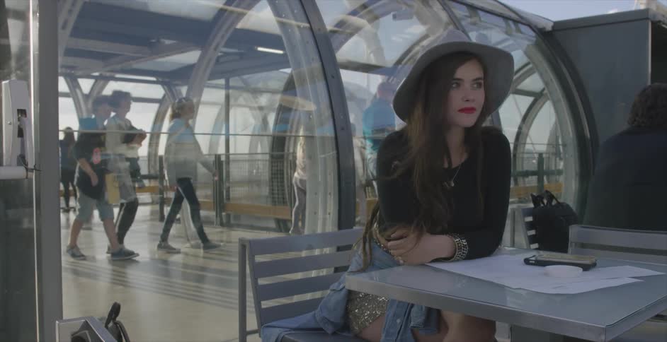 A woman is sitting at a table as people walk behind her